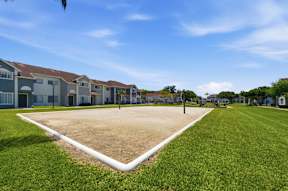 A large grassy area with a white pipe running through it and houses in the background.