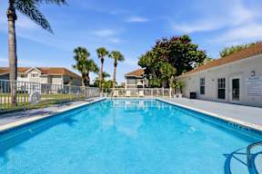 A large swimming pool surrounded by palm trees and residential buildings.