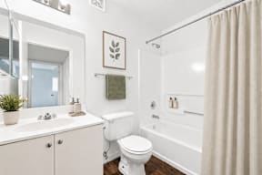 A white bathroom with a toilet, sink, and bathtub.
