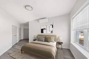 A bedroom with a bed, nightstands, and a window.