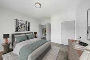 A bedroom with a bed, nightstand, and a painting on the wall.