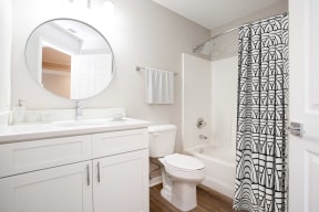 a bathroom with white cabinets and a black and white shower curtain