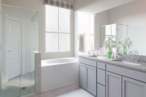 A white bathroom with a tub, sink, and mirror at Walker Place Apartments, Hewitt