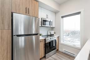 A modern kitchen with a stainless steel refrigerator and oven.at Latitude 49 Townhomes, Manitoba