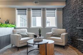 A living room with a stone wall and a round coffee table.at Vista Apartments at Edgemont, Alberta