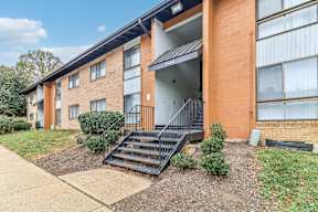 an apartment building with stairs and a sidewalk in front of it at Oaks at Oxon Hill, Oxon Hill, Maryland