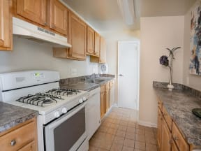 a kitchen with wooden cabinets and a white stove top oven at The Glendale Residence, Lanham, MD