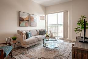 A living room with a couch, a coffee table, and a plant.