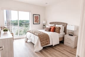 A bedroom with a large bed and a view of the balcony.