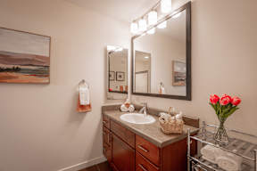 A bathroom with a large mirror, a sink, and a painting on the wall.