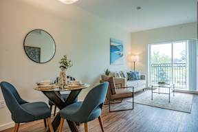 A dining room with a round mirror on the wall and a table set for two.