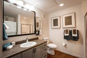 A bathroom with a toilet, sink, and mirror.