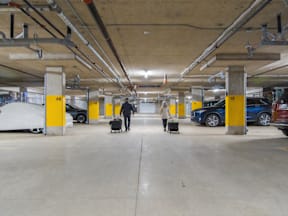 A parking garage with yellow poles and a few cars.