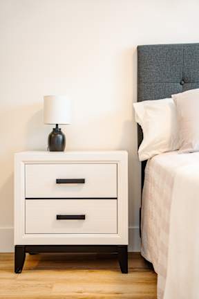 A white nightstand with a lamp on top of it.