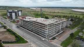 A large multi-story building under construction is surrounded by a highway and other buildings.