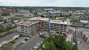 A large building under construction is seen from a distance.