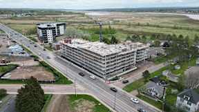 A large building under construction is surrounded by a busy road with multiple lanes of traffic.