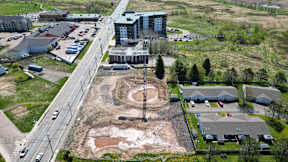 A large building is under construction in the middle of a parking lot.