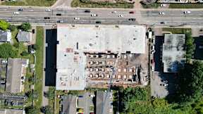 An aerial view of a parking lot and a building with a crane in front of it.