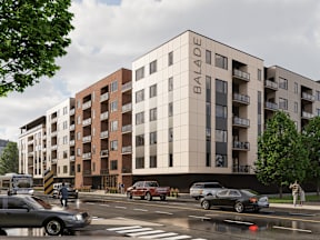 A street view of the Balade apartment building with cars parked and driving by.