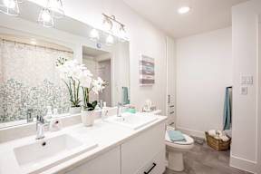 a white bathroom with two sinks and a toilet
