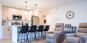 a living room with a kitchen and a counter with bar stools