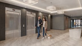 A man and woman walking a dog in a modern hallway.