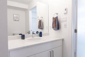 A bathroom with a white counter top and a white sink.