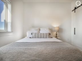 a white bedroom with a bed and a window