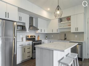 a white kitchen with a marble counter top and stainless steel appliances