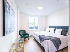 a bedroom with a bed and a chair and a window