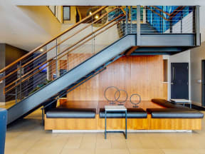 Lobby stair case with stylish seating underneath, wire railings on stairs