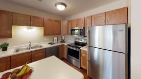Kitchen with light wooden cabinets, central island and stainless steel appliances