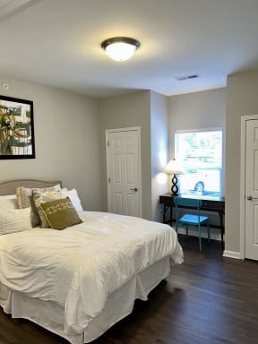 a bedroom with a bed and a desk and a window