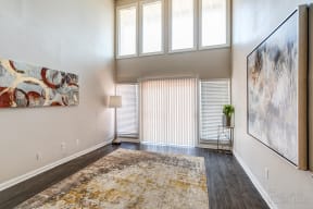 an empty living room with high ceilings and a window with blinds