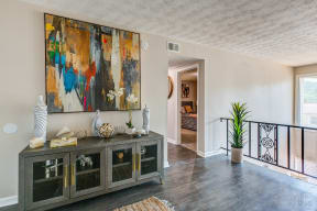 a living room with a large painting on the wall and a cabinet