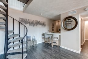 a living room with a spiral staircase and a bar with chairs
