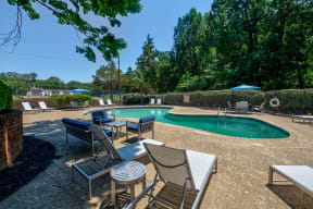 a swimming pool with chairs and tables next to it