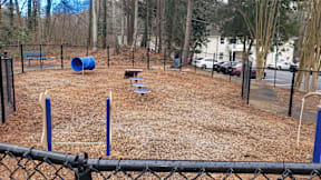 A playground with a blue barrel, a slide, and a bench.