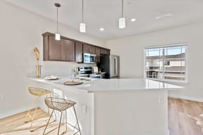 an open kitchen with a large island with bar stools at The Residences Apartments at Bear Tree, DeForest, WI 53532