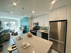 A modern kitchen with a stainless steel refrigerator and a dining table set with plates and bowls.