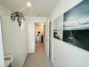 A hallway with a painting on the wall and a plant on the side.