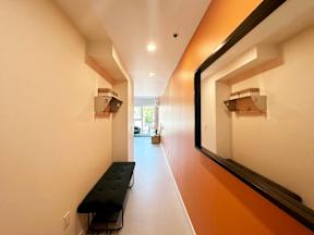 A long hallway with a bench and a window.