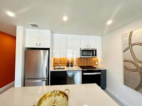 A kitchen with a refrigerator, microwave, oven, and sink.