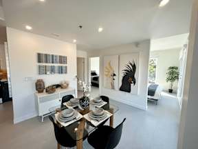 A dining room with a table set for two and a painting of a bird on the wall.