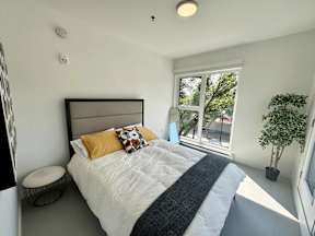 A bedroom with a large bed and a window overlooking a tree.