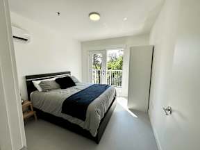 A bedroom with a large bed and a balcony outside.