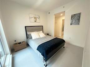 A bedroom with a bed, nightstand, and artwork on the wall.