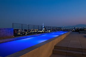 a rooftop infinity pool with the empire state building in the background at night