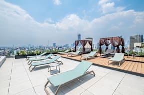 a roof top pool with chaise lounge chairs and a view of the city